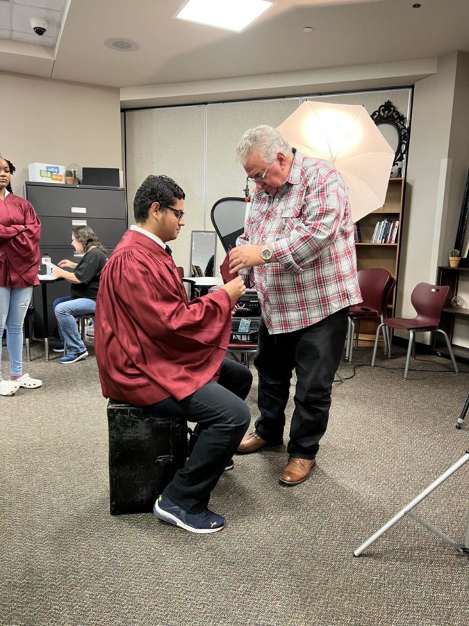 Photographer Scott Tate assists senior Elijah Pena before snapping his portrait.