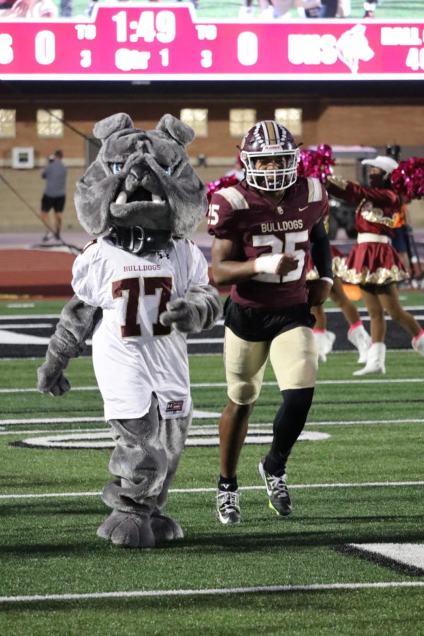 Junior Lloyd Avant runs onto the field with the mascot ahead of the Beaumont United game. Avant is poised for a breakout season this fall.