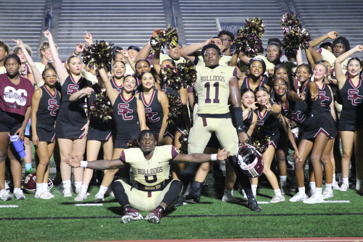 The cheerleaders and football players celebrate their first win of the season. 